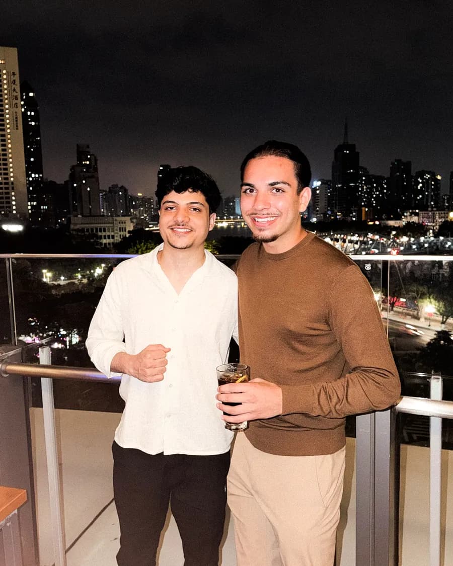 Two team members on a balcony at night, city skyline behind